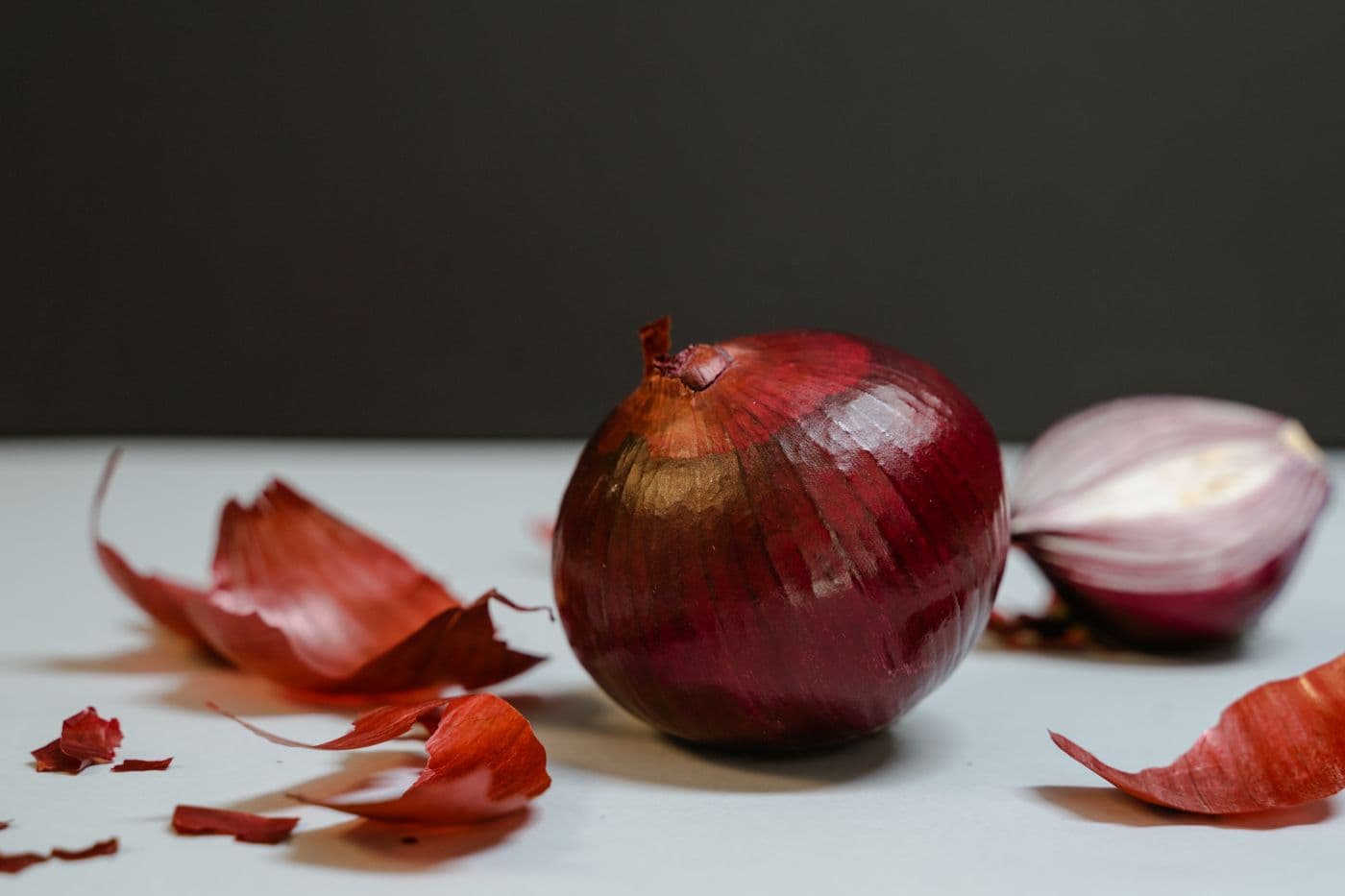 Oignon rouge entier et un demi-oignon, pelures sur fond clair