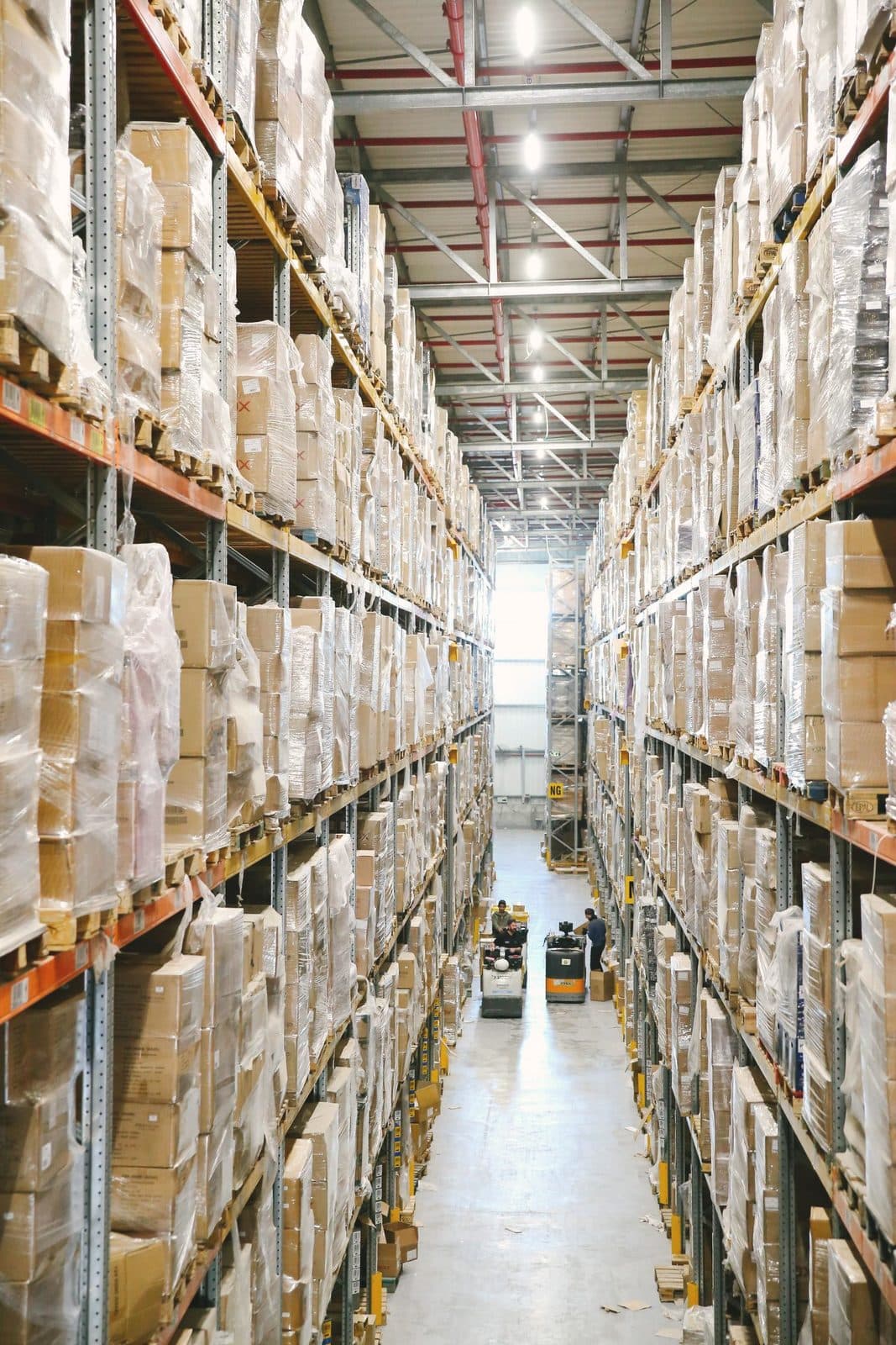 Allée d'entrepôt logistique avec palettes filmées prêtes à l'expédition